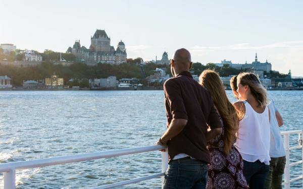 Group of friends aboard the Québec-Lévis ferry, admiring Old Québec in summer.