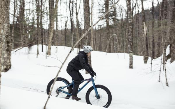 Une personne fait du Fatbike dans la forêt enneigée, dans la Vallée Bras-du-Nord.