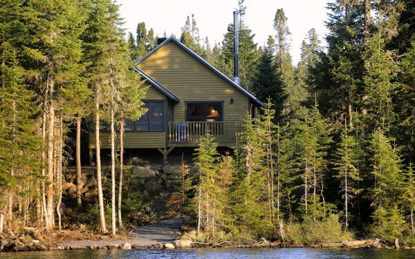 Exterior view of a chalet in the forest, on the edge of a lake, in the Réserve faunique des Laurentides, in summer.