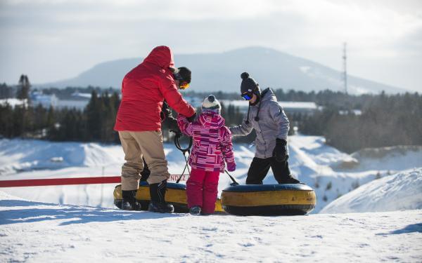 Une famille s'apprête à glisser au centre de jeux d'hiver du Village Vacances Valcartier.