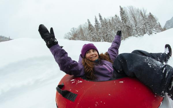A young girl slides on an inner tube in winter, in the Jacques-Cartier National Park.