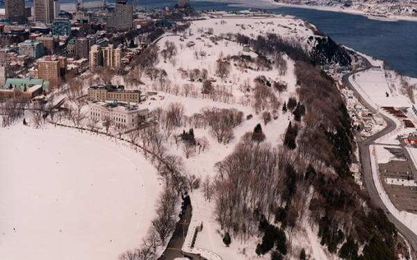 Commission des champs de bataille nationaux - Aerial view of the Plains of Abraham in winter with Old Québec and the St. Lawrence River in the background.