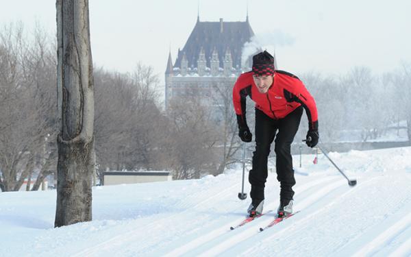 Commission des champs de bataille nationaux - A man cross-country skiing on the Plains of Abraham with the Chateau Frontenac in the background.