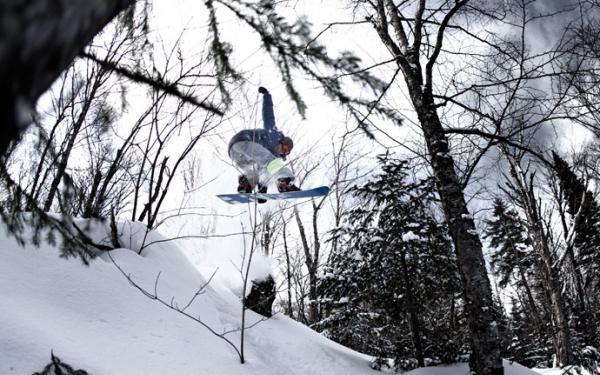 A snowboarder performs a plank jump at Stoneham Ski Resort.