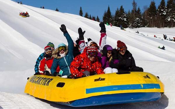 Un groupe de personne fait une descente en rafting des neiges au Village Vacances Valcartier, en hiver.