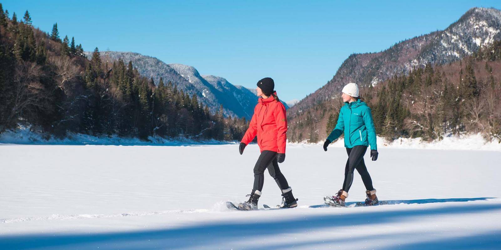 Deux filles en raquette profitent d'une journée ensoleillée d'hiver au parc national de la Jacques-Cartier.