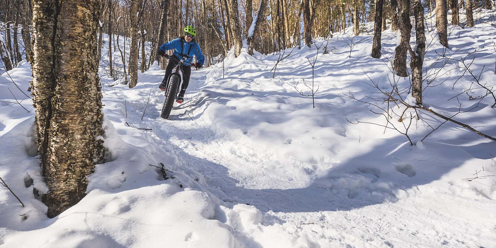 Un adepte de plein air pratique le vélo à roues surdimensionnées dans la forêt enneigée.  