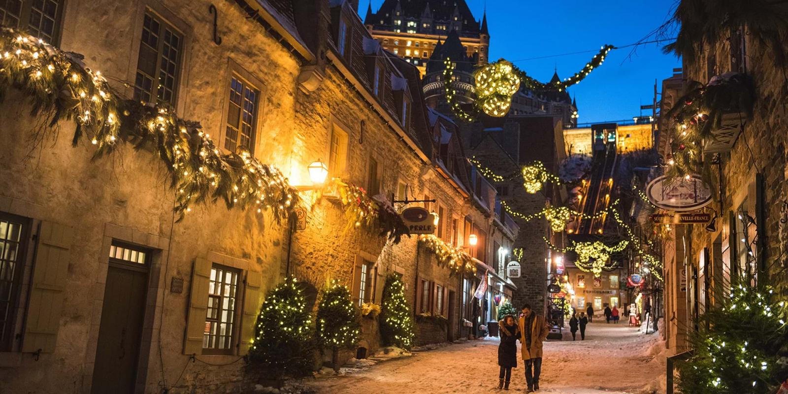 A couple in love walks in the evening in the rue du Petit-Champlain illuminated for Christmas and the holidays.