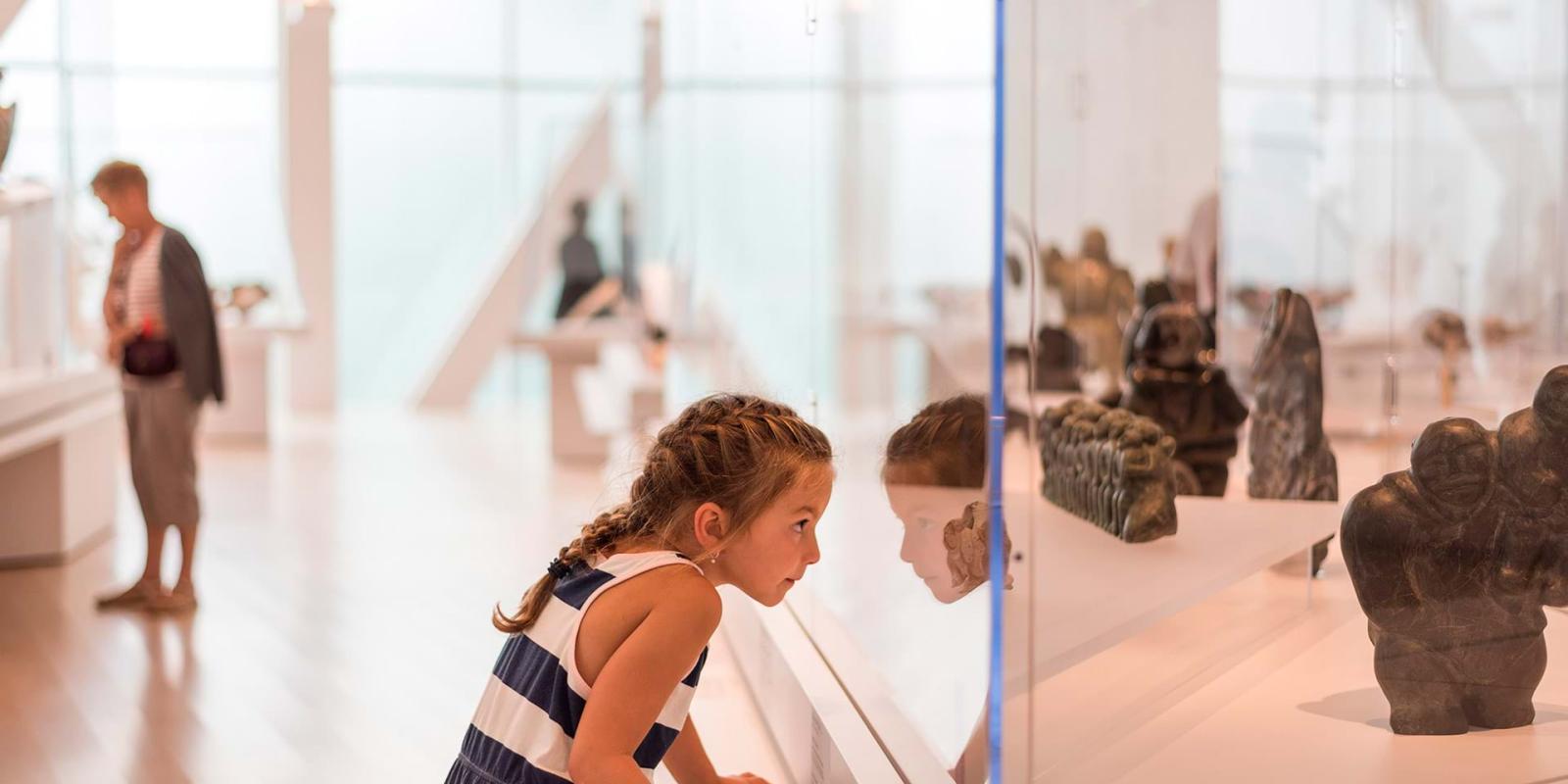 Une fillette regarde à travers une vitrine dans une exposition au Musée national des beaux-arts du Québec.