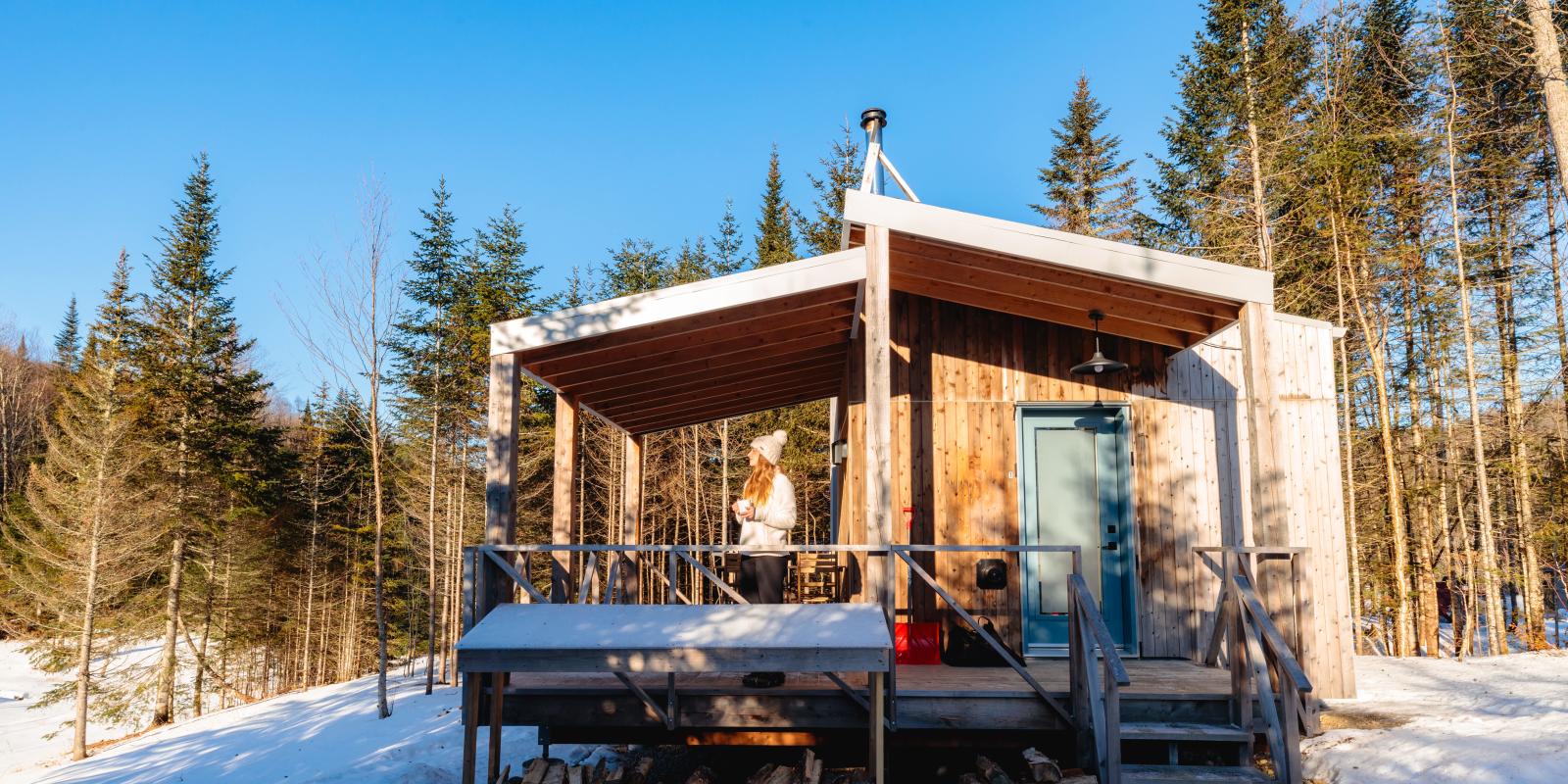 Femme avec un café sur le balcon d'un chalet