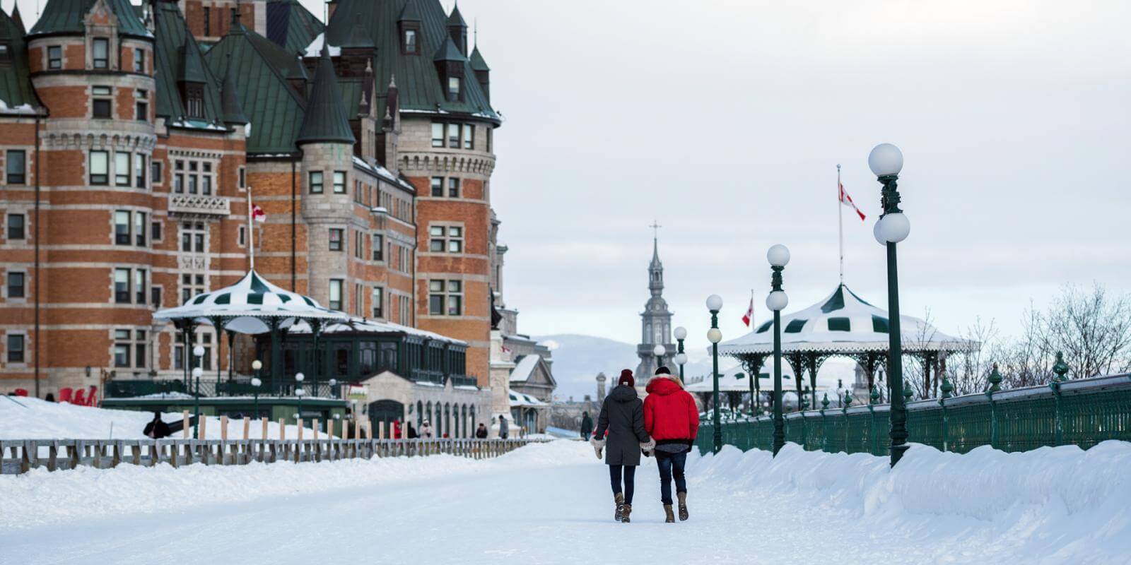 En hiver, deux amoureux marchent sur la terrasse Dufferin, à côté du Château Frontenac.