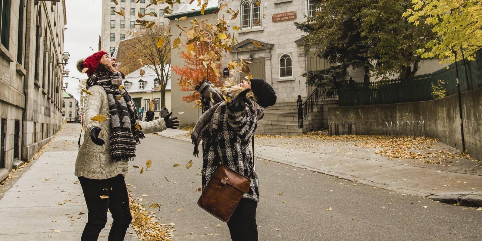 Deux filles lançant des feuilles d'automne dans une rue du Viuex-Québec