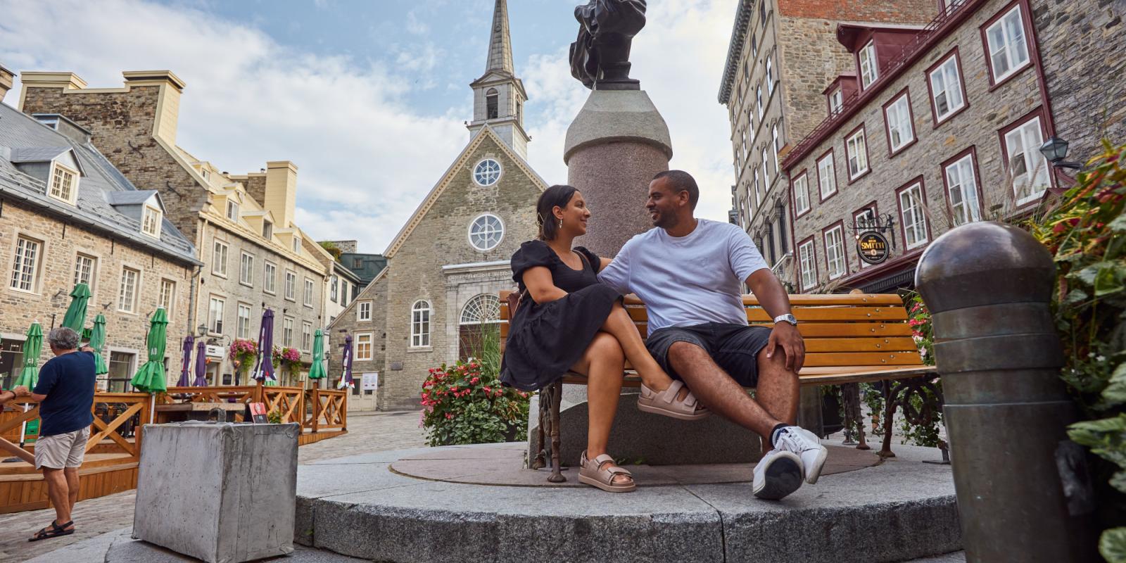 A couple is sitting on a bench on Place Royale