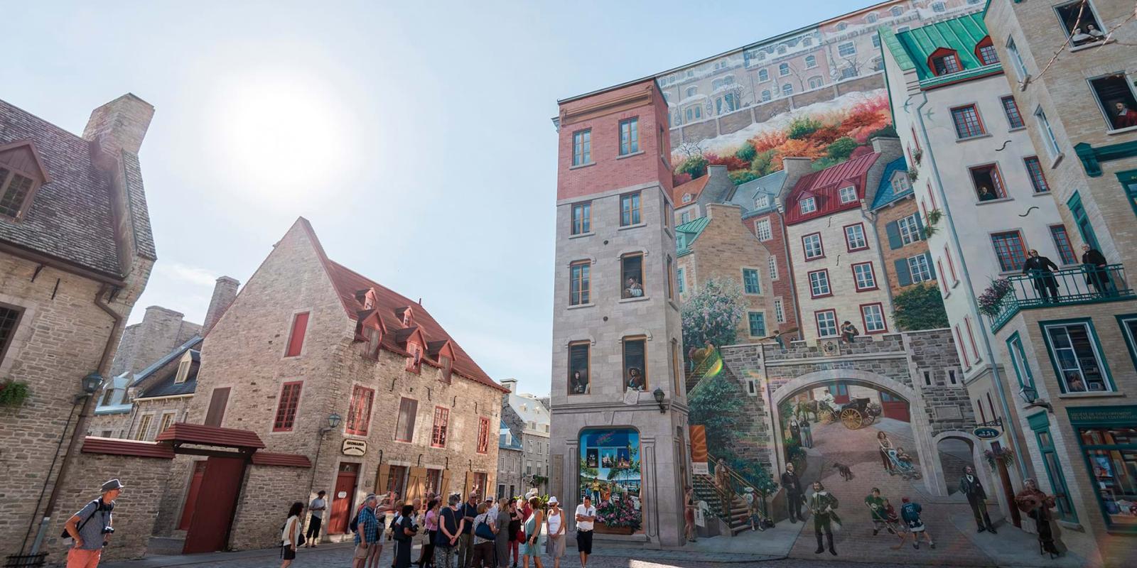 Groupe de touristes observant la Fresque des Québécois dans le quartier Petit-Champlain en été.
