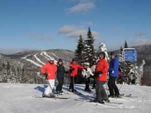 A group of skiers on top of a mountain at Stoneham Ski Resort.
