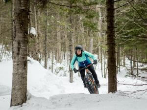 Une personne fait du fatbike dans les sentiers de vélo au Mont-Sainte-Anne, en hiver.