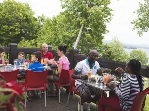 Several people eat outside on the restaurant terrace at the Station touristique Duchesnay.