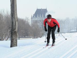 Commission des champs de bataille nationaux - A man cross-country skiing on the Plains of Abraham with the Chateau Frontenac in the background.