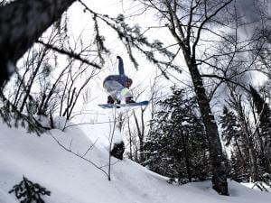 A snowboarder performs a plank jump at Stoneham Ski Resort.