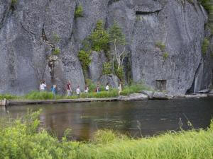 A group of people hikes near a cliff in the Portneuf Wildlife Reserve.