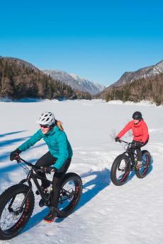 Three people in fatbike are enjoying a sunny winter day in Jacques-Cartier National Park.