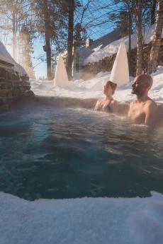 A couple relaxes in a Nordic spa in winter.