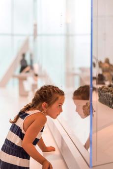 Une fillette regarde à travers une vitrine dans une exposition au Musée national des beaux-arts du Québec.
