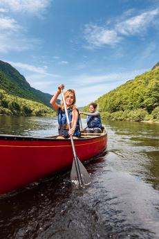Two women canoe in the river at the bottom of the valley, in Jacques-Cartier National Park.