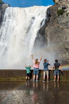 A family gets watered at the foot of the waterfall, in Chute-Montmorency Park, in summer.