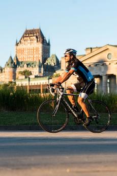 A cyclist rides on a bike path in the Old Port of Québec with the Château Frontenac in the background.