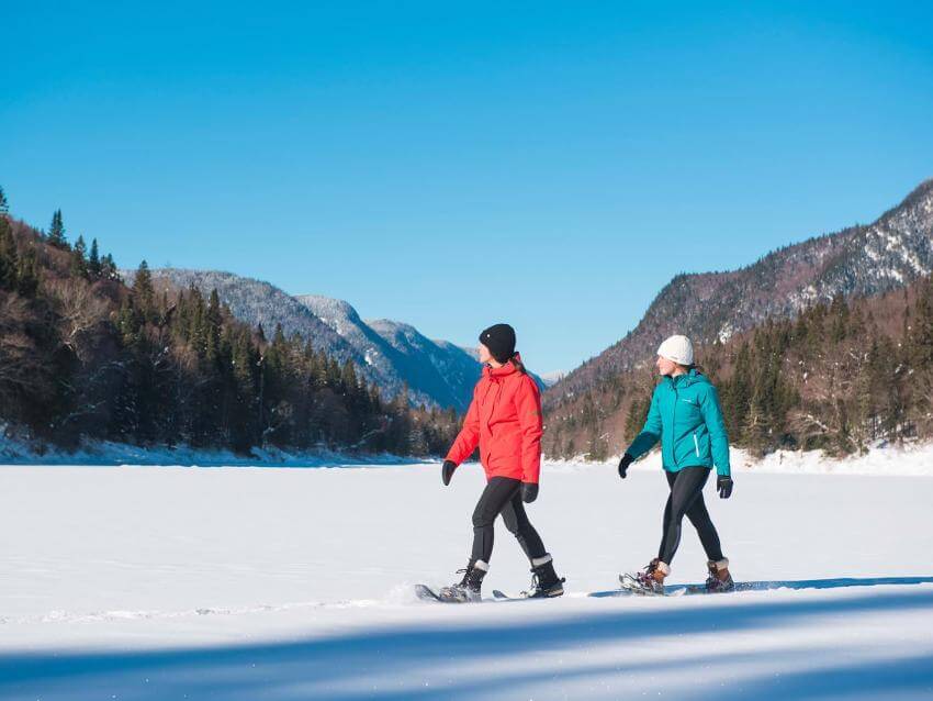 Two girls on snowshoes enjoy a sunny winter day in Jacques-Cartier National Park.