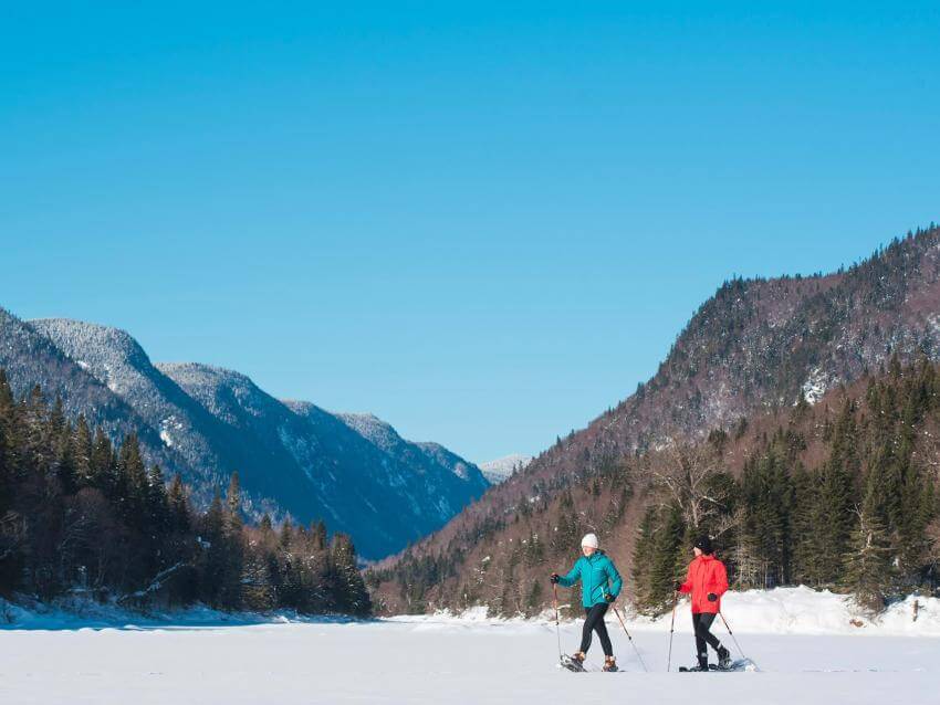 Two girls on snowshoes enjoy the panorama and the great outdoors of the Jacques-Cartier Valley, in Jacques-Cartier National Park.