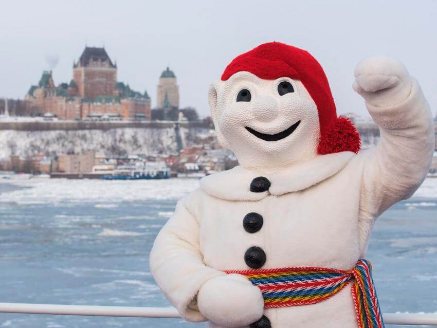 Bonhomme Carnaval proudly poses in front of the Château Frontenac, aboard the Québec-Lévis Ferry.