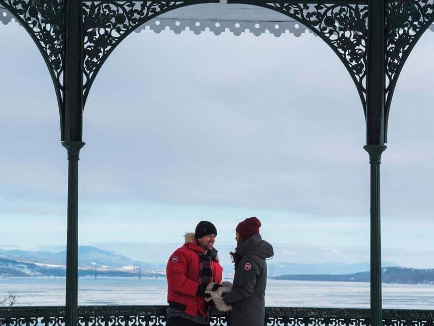 A couple is chatting in one of the kiosks located on the Dufferin Terrace, in front of the St. Lawrence River, in winter.