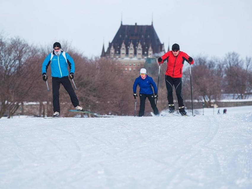 Three skiers practice cross-country skiing on the Plains of Abraham with the Château Frontenac in the background.