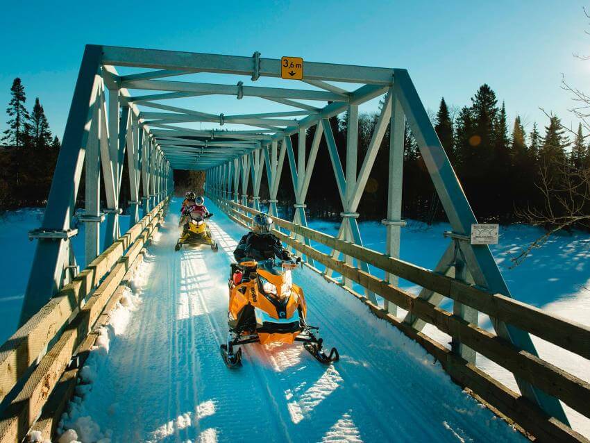 Snowmobiles crossing a bridge in Portneuf