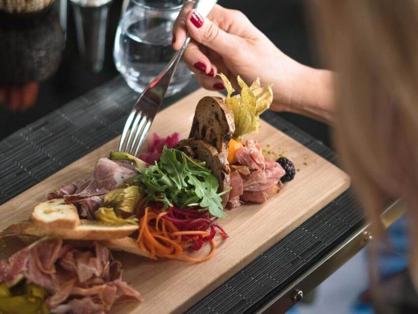A woman eats a meal served on a wooden board in a restaurant in Québec City.