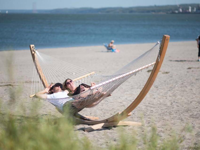 Un couple relaxe sous le soleil, dans un hamac, sur la plage à la Baie de Beauport.