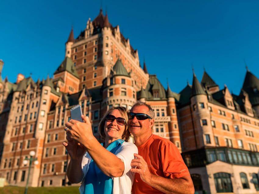 A couple takes a picture of themselves on the Dufferin terrace, in front of the Château Frontenac.