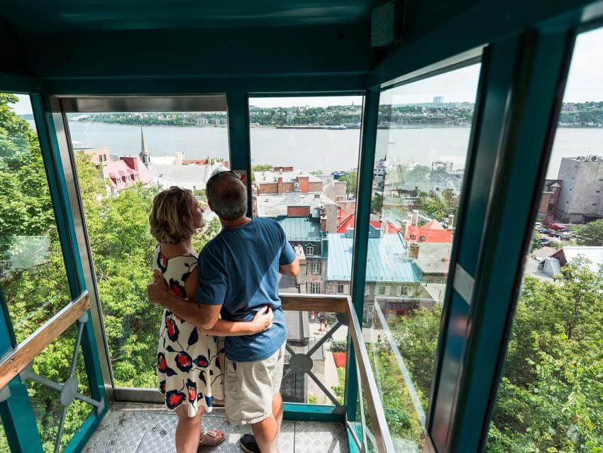 A couple in love admire the St. Lawrence River and the Petit-Champlain district, from the Funiculaire de Québec.