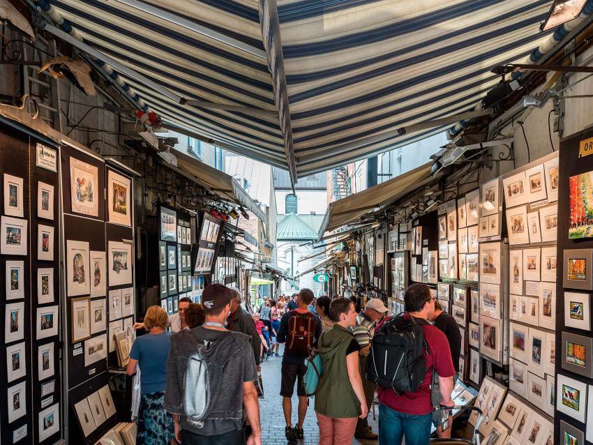 Visitors and artists chat on rue du Trésor, where several artists exhibit their works.