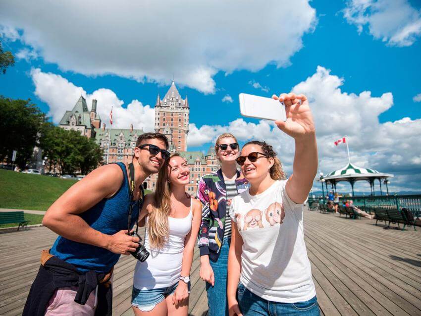 Four young adults take their picture on the Dufferin terrace, near the Château Frontenac.