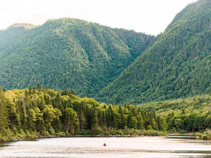 Landscape of the Jacques-Cartier Valley with a distant canoe in the river, in Jacques-Cartier National Park.