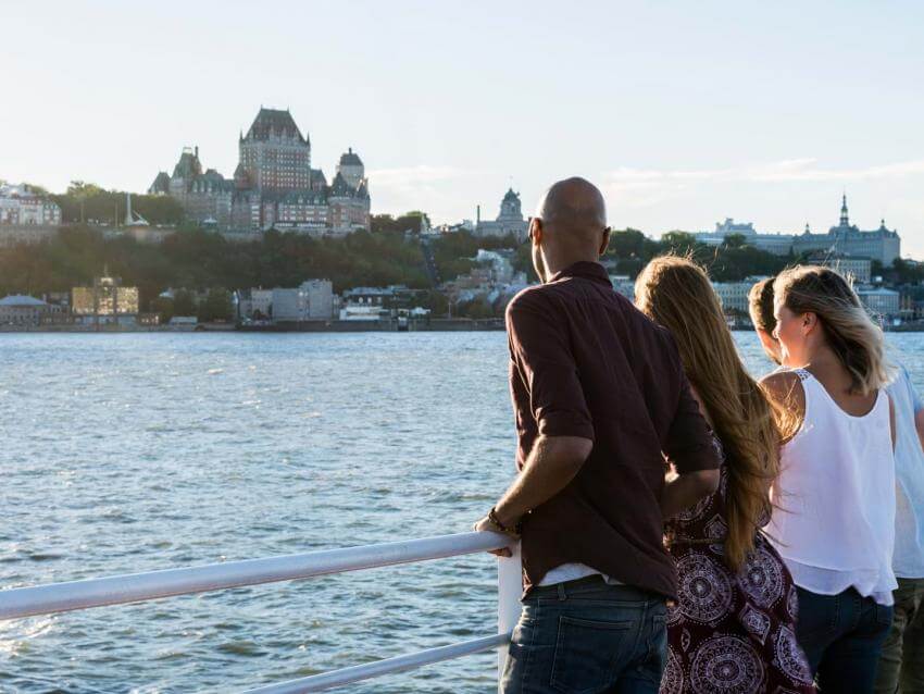 Group of friends aboard the Québec-Lévis ferry, admiring Old Québec in summer.