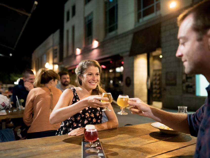 Un couple déguste des bières de microbrasserie sur une terrasse, en soirée.
