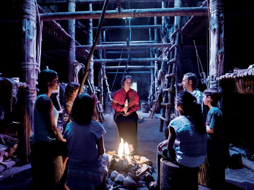 Visitors around a fire listen attentively to an Amerindian legend told by a storyteller in the Wendake longhouse.