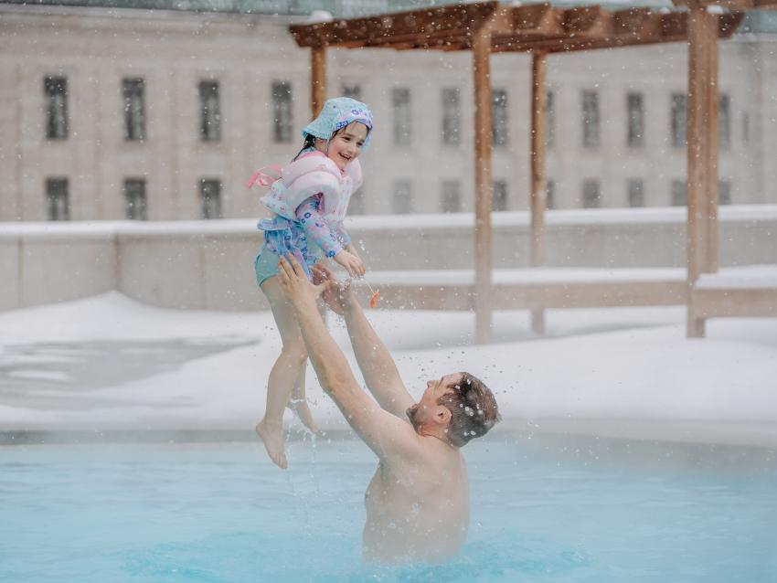 Un père et sa fille dans la piscine extérieure en hiver.