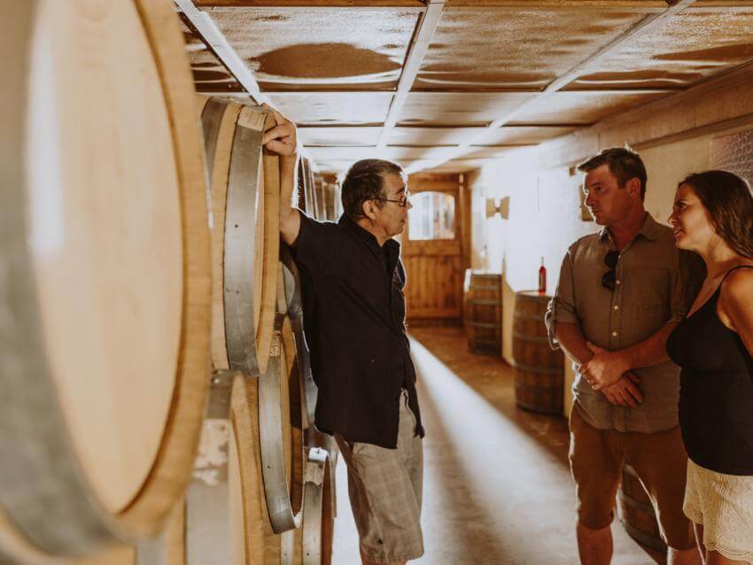Un couple visite une cave à vin de l'Ile d'Orléans avec un guide touristique.