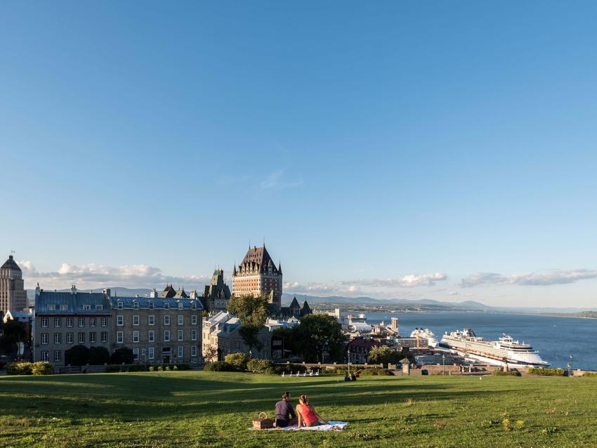 Couple picnic near the Pierre-Dugas-De Mons terrace, in front of a panorama of Old Québec and the St. Lawrence River.