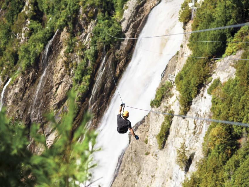 Un homme traverse l'anse de la chute en tyrolienne au Parc de la Chute Montmorency.